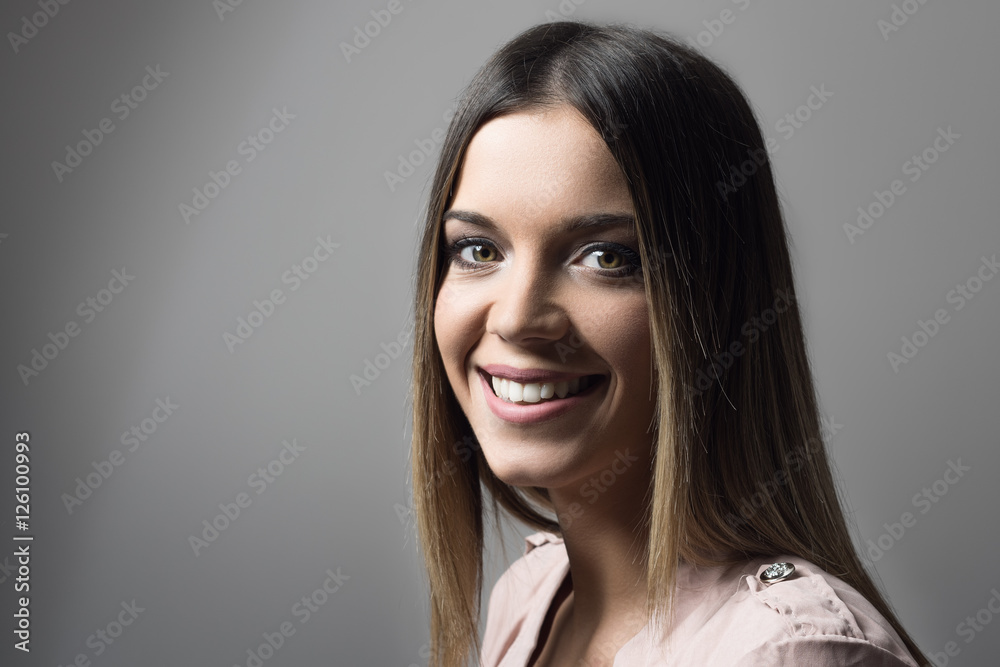 Atmospheric portrait of young beautiful woman smiling and looking at camera over the shoulder Atmospheric portrait of young beautiful woman smiling and looking at camera over the shoulder