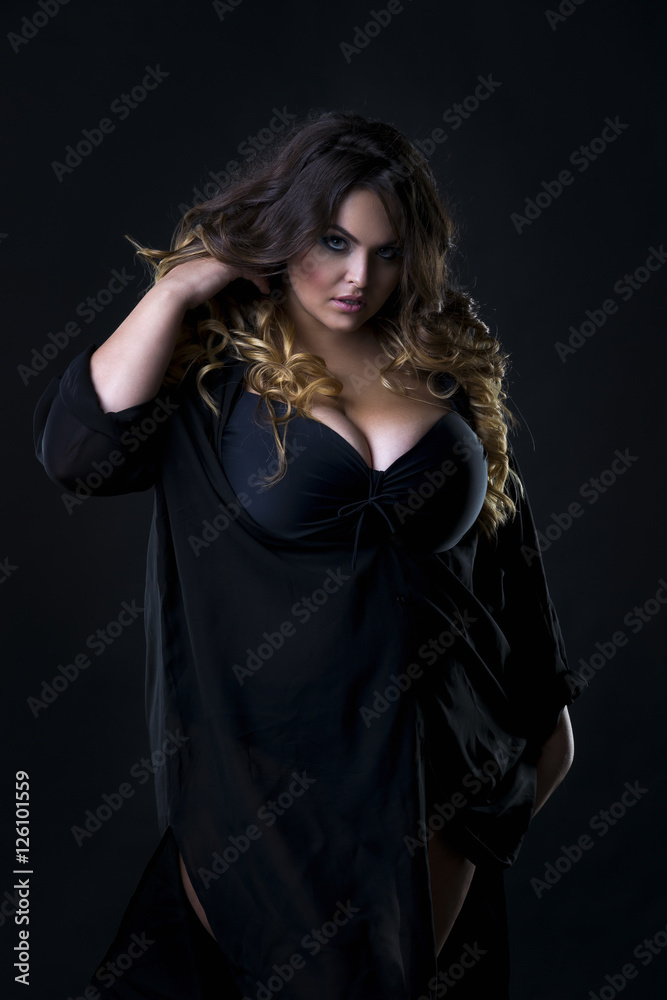 Young beautiful plus size model in underwear, xxl woman on black background