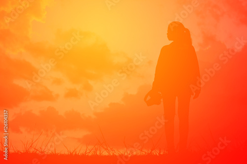 Silhouette women with camera on the sky sunset concept travel ,alone in nature ,vintage tone