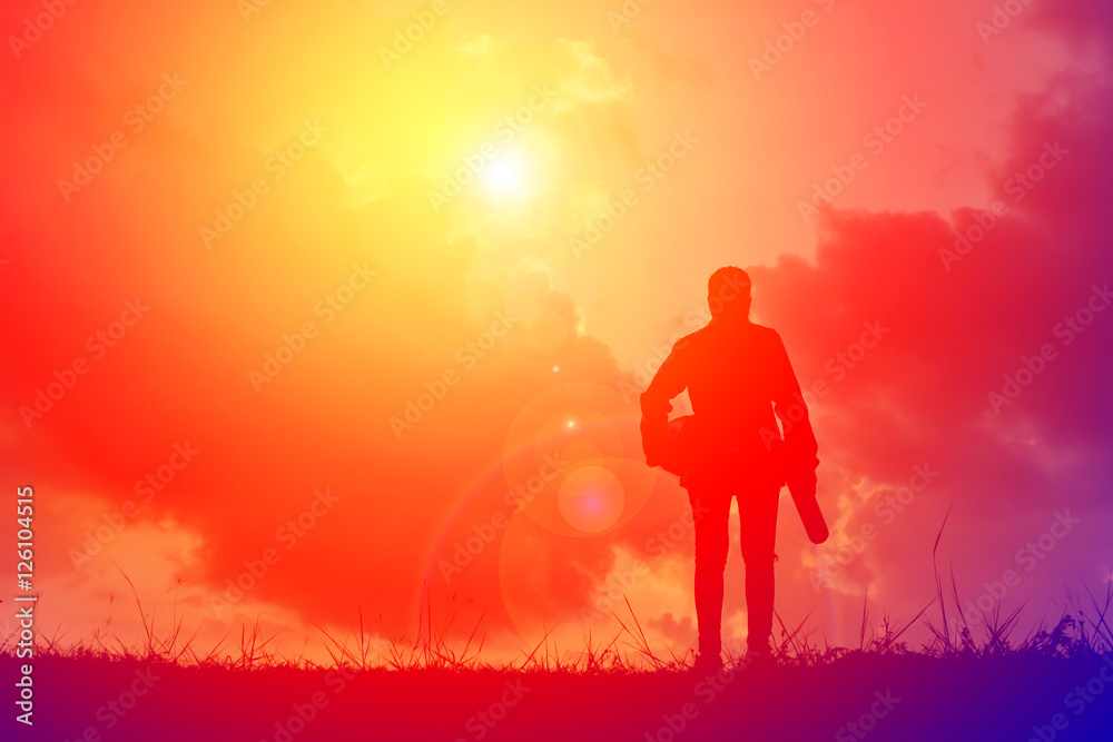Silhouette engineer with a blueprint on the sky sunset. vintage tone and selective focus Silhouette engineer with a blueprint on the sky sunset. vintage tone and selective focus