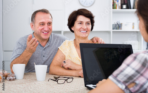 Smiling senior couple listening to young woman