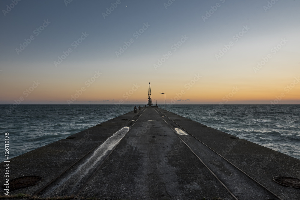 Marine concrete pier with crane at sunset