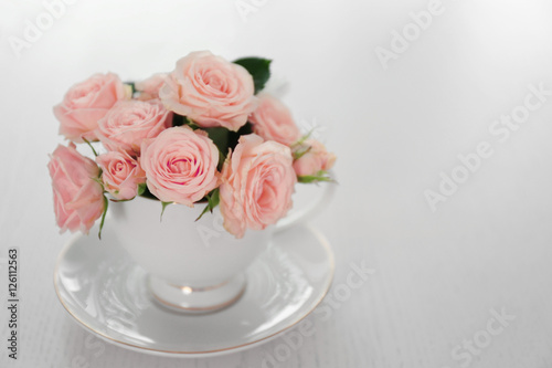 Bouquet of beautiful roses in a cup on a  table