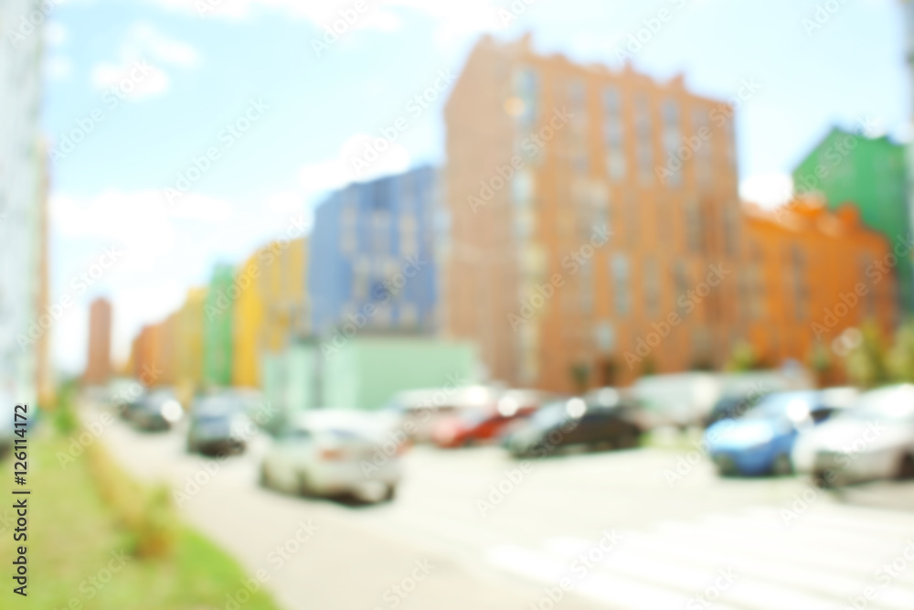 Blurred view of parked cars near modern colorful buildings