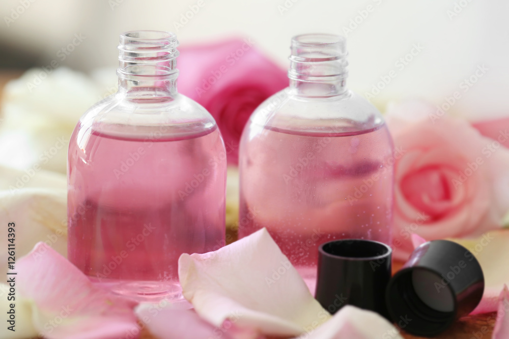 Essential oils with flower petals on wooden table