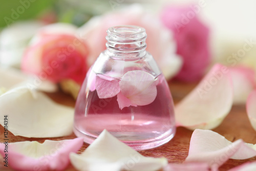 Essential oil with flower petals on wooden table