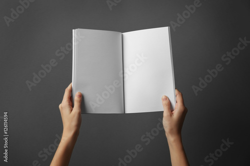 Fototapeta Naklejka Na Ścianę i Meble -  Female hands holding blank open brochure on grey background