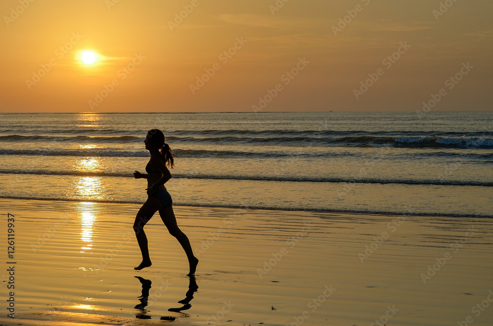 Silhouette of woman jogger running on sunset beach, fitness and healthy life concept
