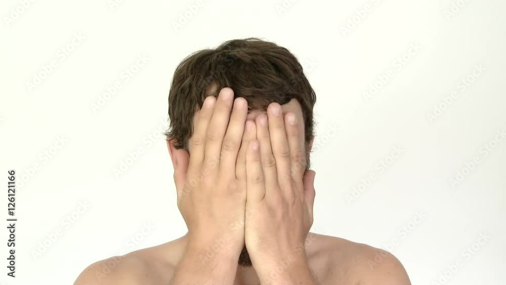 Model released man in studio hiding his face, looking cautiously then reveals a happy smile. Model released man in studio hiding his face, looking cautiously then reveals a happy smile.