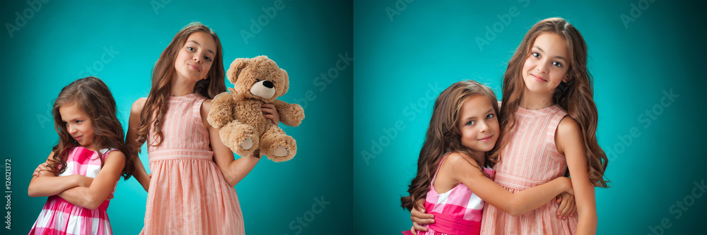 The two cute little girls on blue background with Teddy bear The two cute little girls on blue background with Teddy bear