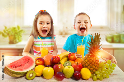 Kids with fruits and fresh juice in kitchen, healthy eating