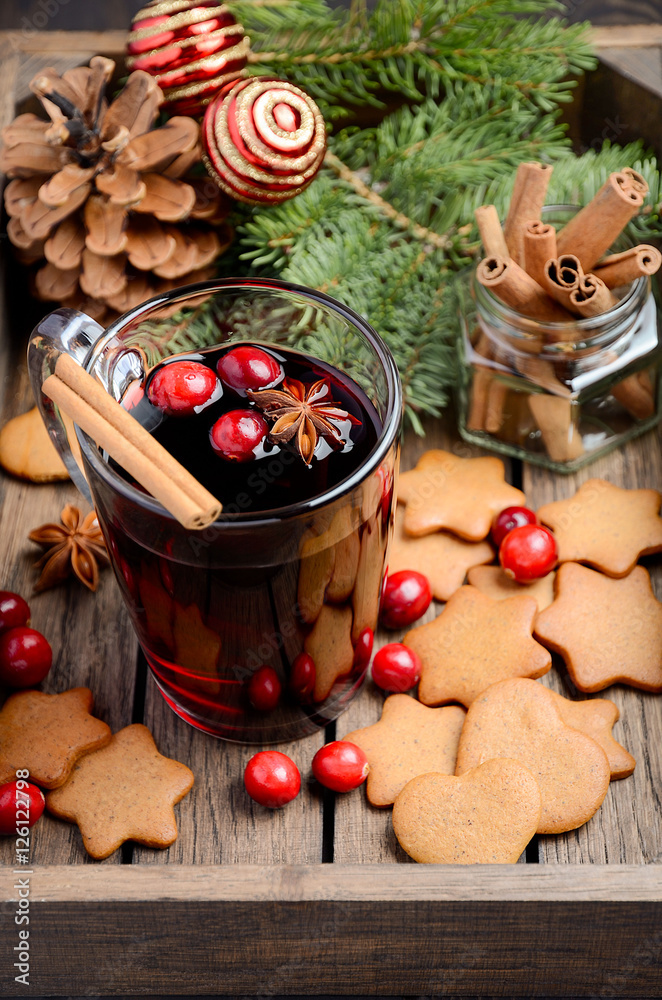 Christmas mulled wine. Holiday concept decorated with Fir branches, Gingerbread Cookies and Cranberries on dark wooden tray. Selective focus.    