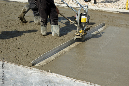 Smoothing concrete with gas powered vibrating screed machine