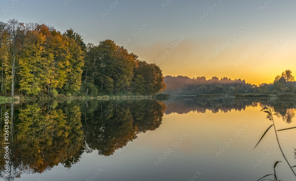 Colorful sunset in autumnal forestry lake, Europe