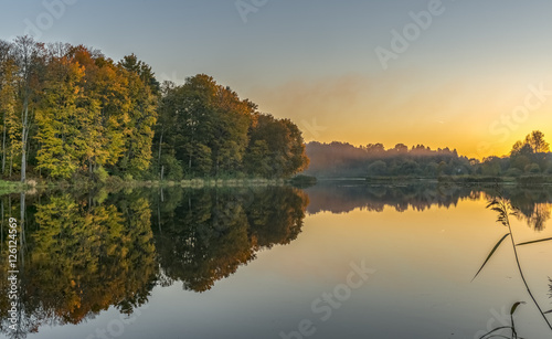 Colorful sunset in autumnal forestry lake, Europe