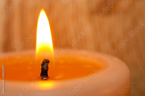 Burning candle closeup on light background.