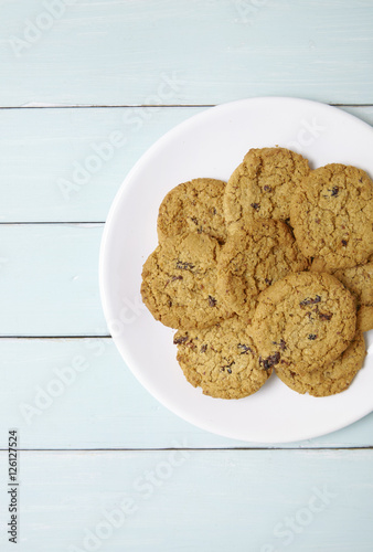 Aerial view of a plate full of freshly baked oatmeal and raisin cookies on a painted wooden background