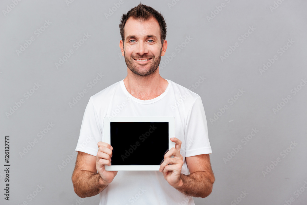 Smiling casual man showing blank tablet computer screen Smiling casual man showing blank tablet computer screen