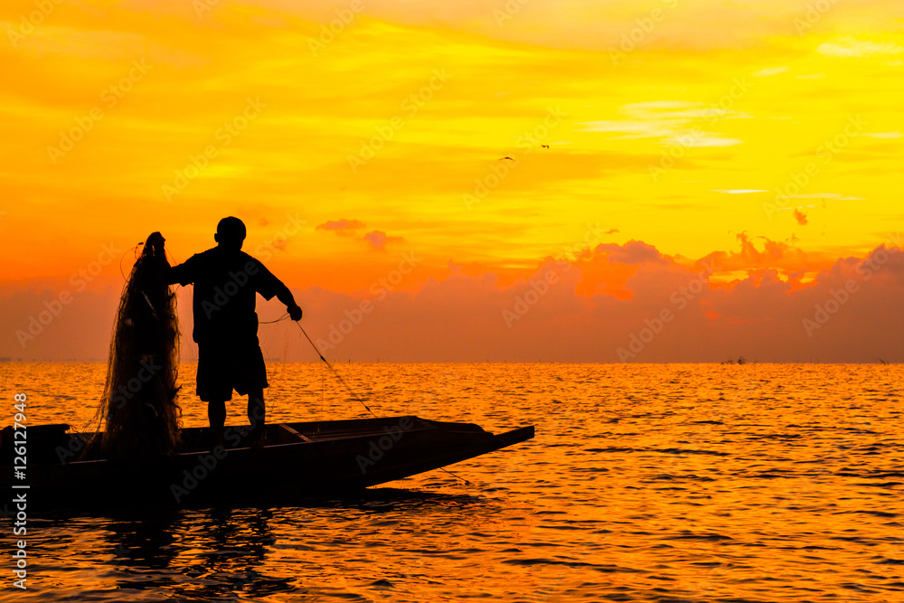 Silhouette of Fishermen fishing in the lake at the sunrise time.