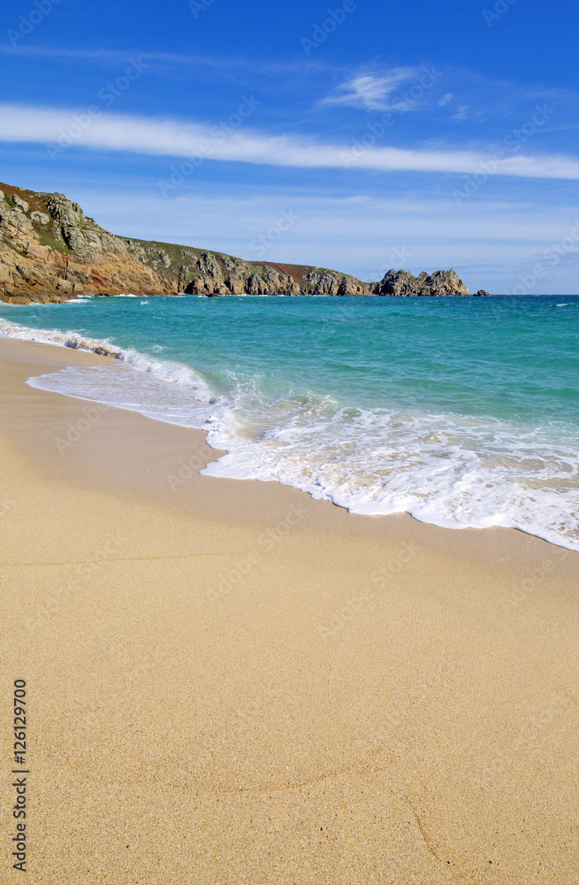 Porthcurno sandy beach and Logan rock in Cornwall England.