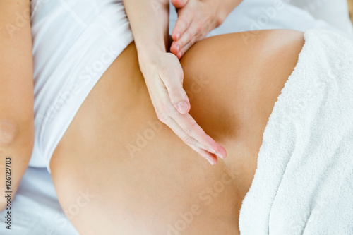 Beautiful pregnant woman having a massage in spa.