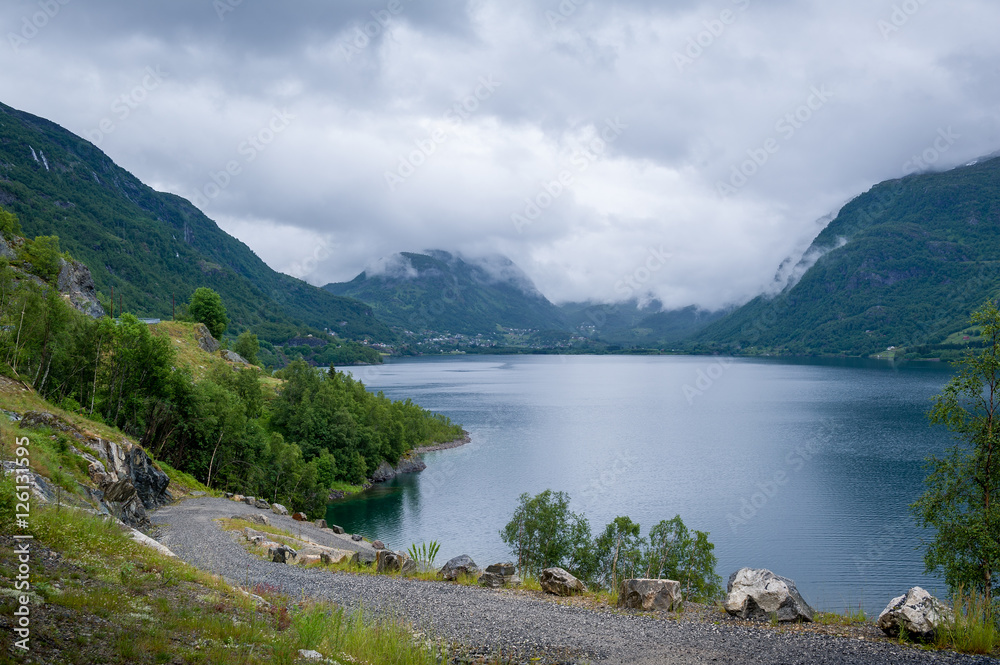 Gravel road at norwegian beautiful fjord shore.