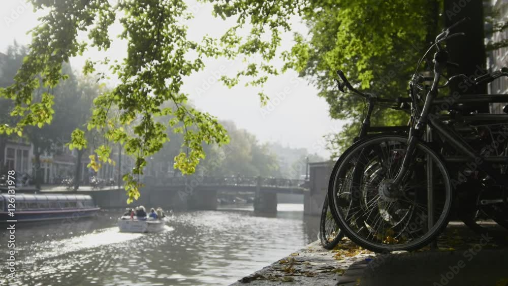 View of wheel of bicycle on the Amsterdam amstel canal, next to floats tour boat, sunny european autumn