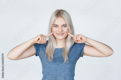 Young woman with fingers pointing to her dimples photo