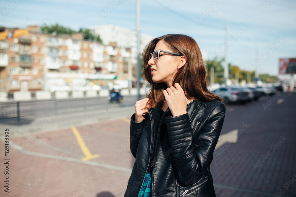 Urban fashionable girl posing in a leather jacket outdoors in the city