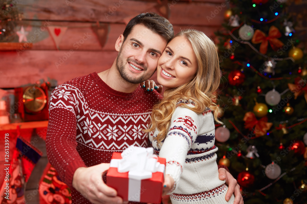 young man and woman holding a wrapped gift young man and woman holding a wrapped gift