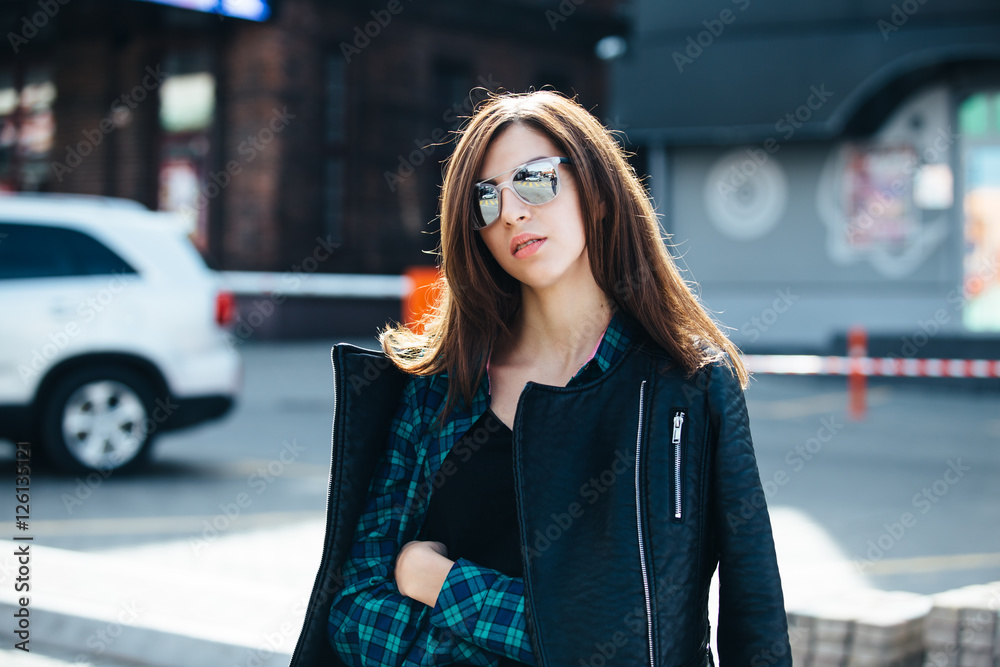 Brunette girl in rock black style, standing outdoors in the city street