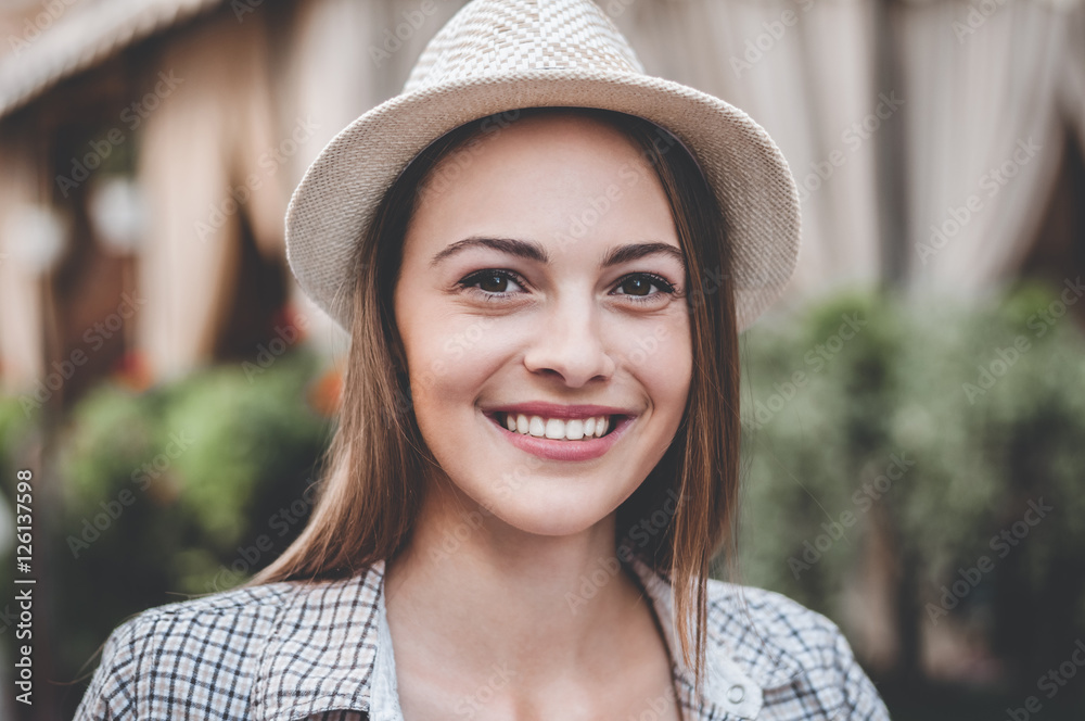 Urban beauty. Beautiful young woman in hat smiling while standing outdoors