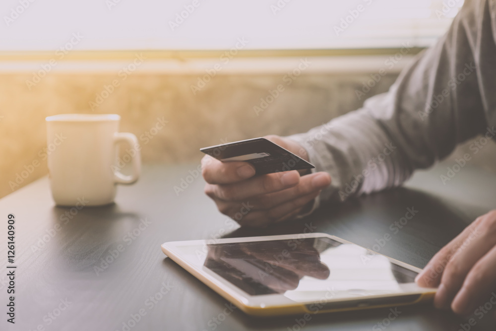 Male hands holding credit card and using Tablet on the table Male hands holding credit card and using Tablet on the table