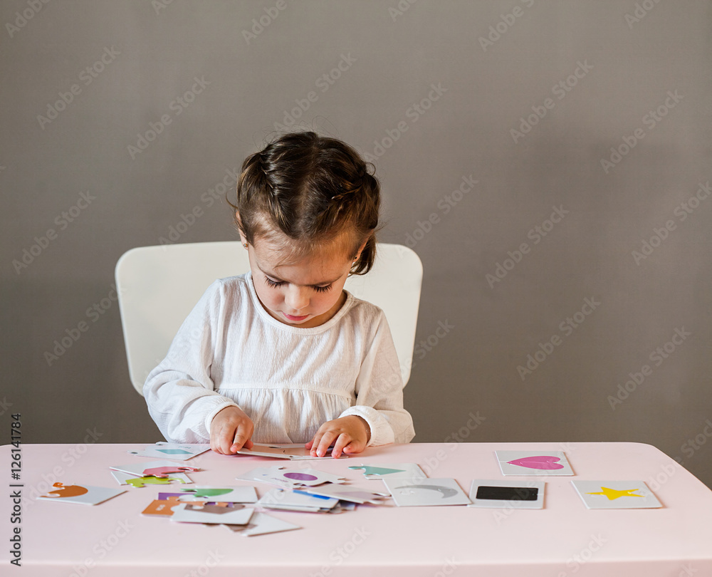 Cute little girl in white shirt playing puzzle. Process of education, cognition Cute little girl in white shirt playing puzzle. Process of education, cognition
