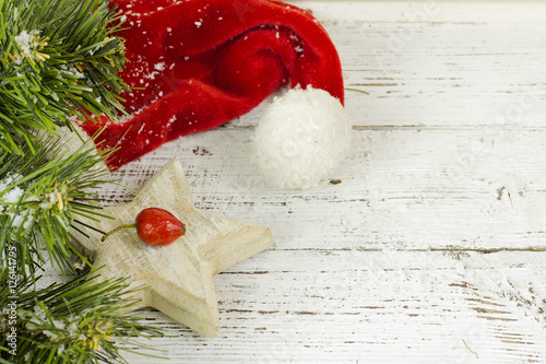 Christmas fir tree with red hat and snow on a wooden background