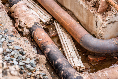 Excavation pit. Old drink water pipe with stainless repairing sleeve members. Finished repaired piping waiting for covering by clay. Asphalt isolation.