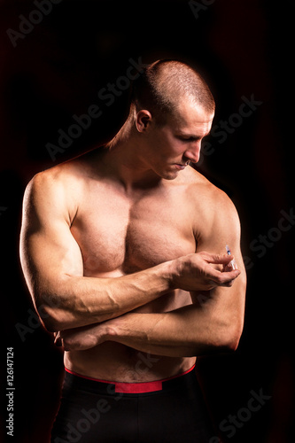 bodybuilder man injects steroid with injection needle isolated on black background