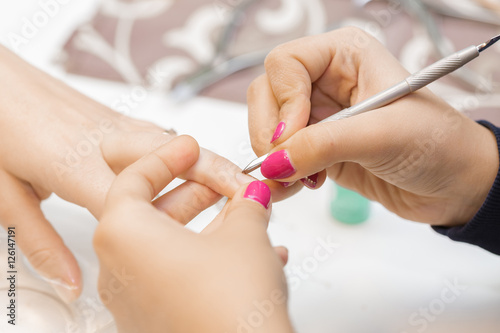 Manicurist uses  professional manicure tool.
