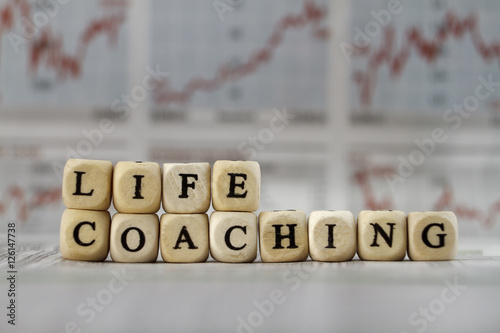 Life coaching word built with letter cubes on newspaper background