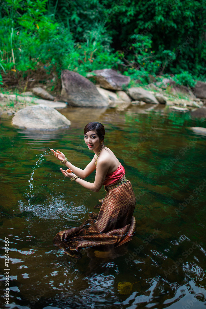 Fototapeta premium Beautiful girl with Thai dressing was playing water in the river.