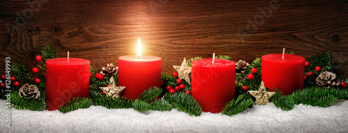 Advent Dekoration mit einer Kerzenflamme, Schnee, Tannenzweigen und Holz Hintergrund photo