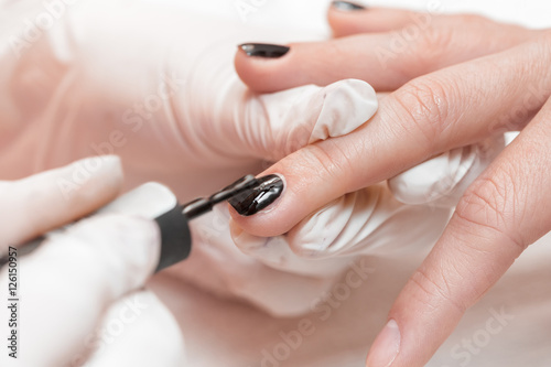beautician applying Polish nails to women 