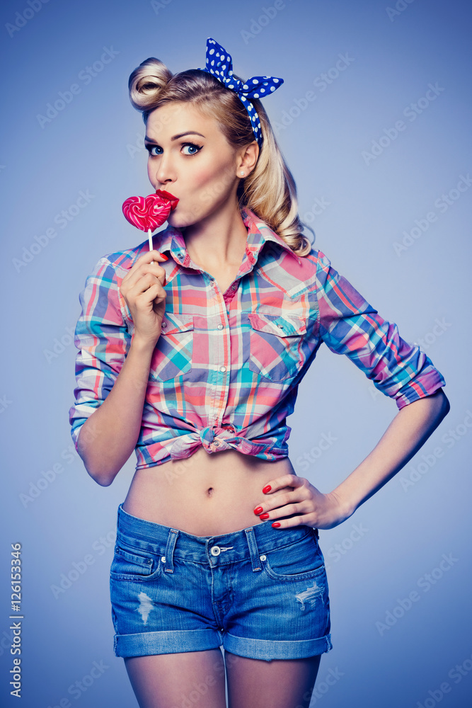 woman eating heart shape lollipop, dressed in pin-up style