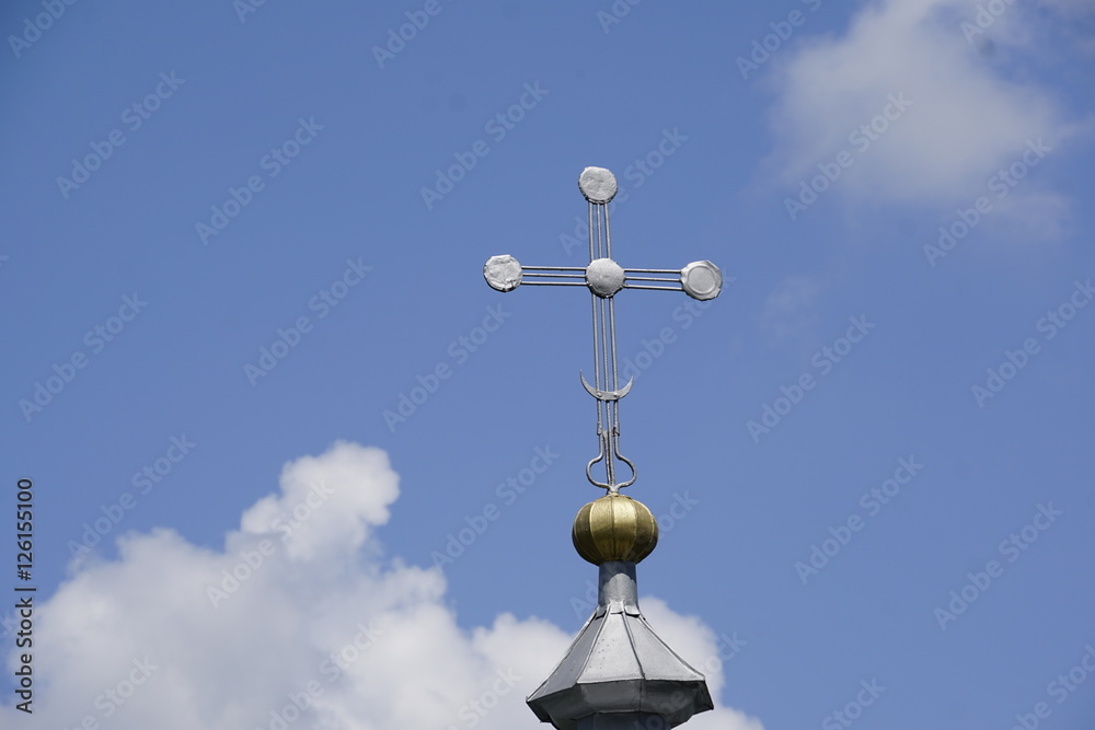 cross on top of a church in front of bright blue sky