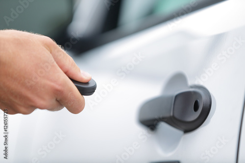 Obraz na plátně Man locking car door using remote control key fob