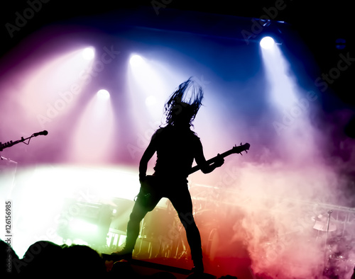 silhouette of guitar player in action on stage in front of concert crowd