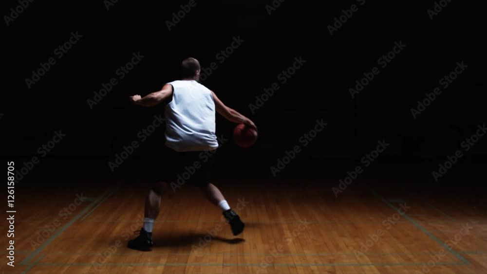 Wide shot of a basketball player dribbling a ball and then shooting it Wide shot of a basketball player dribbling a ball and then shooting it