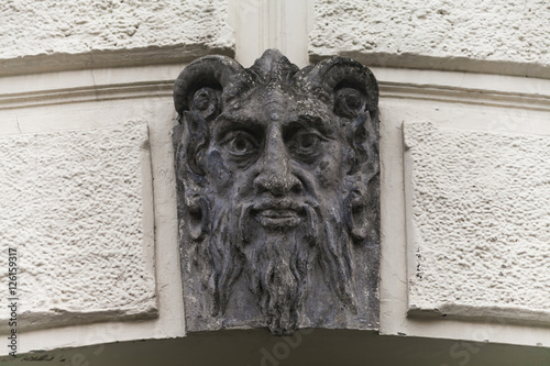 Sculpture of Lucifer face with horns. Demon evil mascarone architecture element building's facade background. Shallow depth of field photo