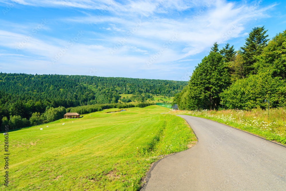 Road alongside golf course green area in Arlamow village, Bieszczady Mountains, Poland