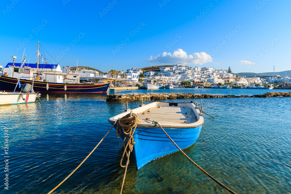 Traditional white and blue color Greek fishing boat in Naoussa port at sunset time, Paros island, Greece